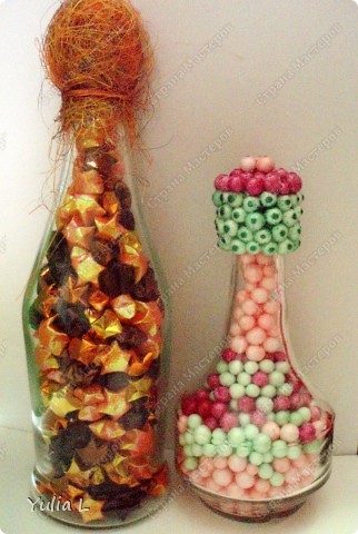Две подарочные бутылки, но такие разные по скорости выполнения. Маленькую сделала дочуня для бабушки; наполнитель - пенопластовые шарики, крышку обклеили при помощи клеевого пистолета. В большой бутылке - звездочки счастья для папы, крутили несколько вечеров. Пробка декорирована флористической сизалью. 
МК можно посмотреть здесь http://blog.kp.ru/users/murlis/post149069952/ (фото 1)