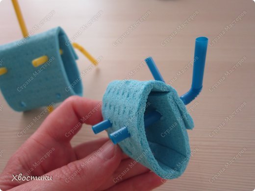 Трубочки для головы вставляем через совмещённые отверстия и высовываем через дырочки на "лице" робота. Гофра остаётся на затылке. Её сразу можно загнуть, развернув усики-антенны вверх и в стороны. (фото 10)