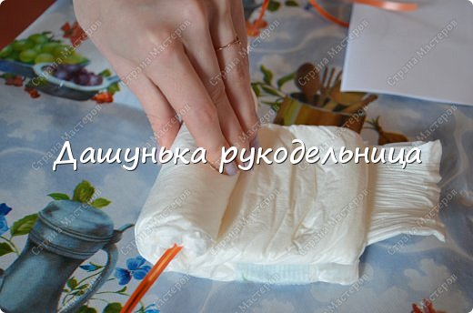 Скажу заранее-ушло всего 16 памперсов!(если правильно подсчитала :) ).Так как дома нашла запас памперсов разных размеров,то так и решила,что поделка будет так сказать "на вырост",да и вид всей "конструкции" от этого становится более интересным..Первым шагом-взяла два памперса самого большого размера(дабы будущие "колёса" были большими),и не разворачивая их начала скручить ПЛОТНО в такой рулетик.При этом внутрь памперса нужно положить крепкую ленту или нить,чтобы потом всё прикрепить к общей конструкции (фото 2)