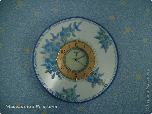Вот такие часы получились у меня. Идею подсмотрена где-то на просторах интернета, правда, там цветы были декупажные. Изначально часы предполагалось делать в сине-белых тонах, под цвет комнаты.
При изготовлении этих часов мне понадобилась мужская сила. Мужская сила в лице любимого вырезала круг из ДСП, отшлифовала и прикрепила к нему сами часы (купленные в магазине "Всё по 12"). Круг я покрасила акриловой аэрозольной краской. Пригодился случайно завалявшийся мебельный ободок синего цвета, который мы прикрепили по краю. Диаметр круга оказался великоват, но переделывать не стали, пусть будет с размахом))). (фото 1)