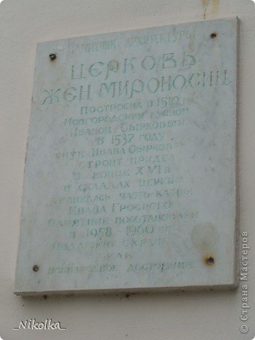 Надпись: «Памятник архитектуры. Церковь Жен Мироносиц. Построена в 1510 г Новгородским купцом Иваном Сырковым. В 1537 году внук Ивана Сыркова строит придел. В конце XVI в в складах церкви хранилась часть казны Ивана Грозного. Памятник восстановлен в 1958-1960 гг. Подлежит охране как всенародное достояние» (фото 9)