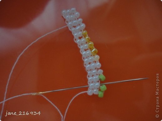 затем возвращаемся через соседний ряд к лицевой стороне, но иглу не продеваем через самую ближнюю зеленую бисерину, а выходим перед ней (фото 30)