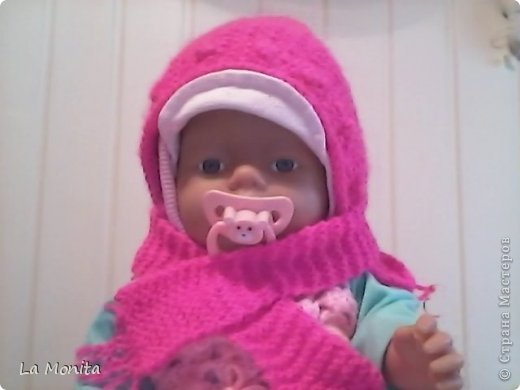 Моей сестрёнке Насте (2 годика) купили куклу Baby Born. Из одежды у неё только зелёный спортивный костюмчик, шапочка с козырьком, да носки. Вот я и решила помочь малышке. Связала вот такой комплект: тёплая шапка и шарфик. Использовала нитки 100% шерсть, цвет: фуксия. Вязала спицами самым простым способом. (фото 1)