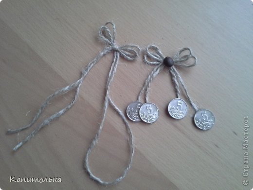 Для декора нам надо сделать бантик. Берем см 35-40 шпагата (можно см 20-25, но тогда тяжело справиться с бантиком), складываем его пополам, завязываем бантик. Я завязываю без узелка, не так толсто получается.
На кончики приклеиваем монетки в понравившемся месте, на разной длине, отрезаем кончики шпагата. Приклеиваем красивое зернышко кофе. (фото 15)