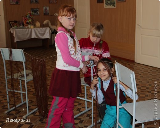 Парик сделали мои подопечные маленькие мастерицы из старых кассетных лент(аудио) ....помните которые от магнитофонов. На парик ушло около 40 таких кассетных лент. Сначала мы подготовили два стула, привязали к спинкам стульев нить (можно отрезок пряжи, можно тонкий жгут-бечевку), на эту нить необходимо одеть ленты-волосы. Детки нарезали на полоски (длинные) кассетную ленту, складывали их пополам и продевали петлёй через нить (вешали на нить и затягивали петлю). Петля, как на закладки вешаем ленту атласную. (фото 22)