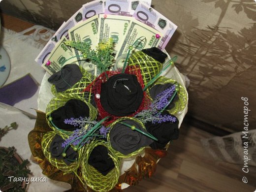 Для букета потребовалось:
5 пар носков.
9 конфет "Золотая лилия"
3 искусственные веточки (2 фиолетовые и 1 желтая)
пучок искусственной травки (получилось 7 травинок)
немного красной и зеленой сетки
бутафорские деньги
гофрированная бумага
немного разных бусинок и стразиков
ленты разного цвета и ширины
9 шпажек.
(фото 2)