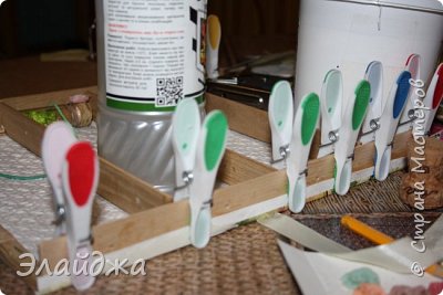 Таким образом вставляю и приклеиваю полочки со всех сторон. Для фиксации пользуюсь прищепками . В боковых планках еще до приклейки необходимо просверлить дырочки для резинок, что будут держать наши бутылочки. (фото 7)