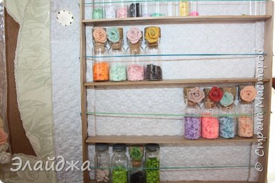 Все палочки от мороженного, что служат нам внутренней рамкой, я тоже обклеила бумагой, чтоб скрыть их.Да и на белом фоне цвета лучше видны. Оставила только рамку внешнюю деревянной. Фактура красивая я и морилкой передумала тонировать. Теперь можно заселять конструкцию бутылочками. (фото 14)