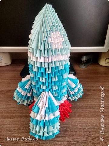 Выполнена из модулей 1/32 по технике МК https://alegri.ru/rukodelie/origami/modulnoe-origami/modulnoe-origami-kosmicheskaja-raketa.html
 (фото 1)