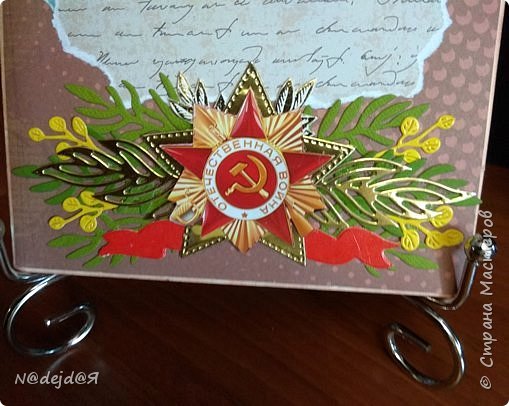 Поближе посмотрим нижнюю часть открытки.
В центре звезда, которую я вырезала из  почтовой открытки. Под эту звезду я вырубила из золотого картона звезду размером побольше.
По краям вырубила зелень. и ленточку красную.  (фото 4)